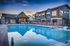 Luxurious outdoor pool area at modern townhome complex, featuring stylish architecture and vibrant lounge chairs under a beautiful sunset sky.
