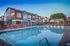 Chic apartment complex with a refreshing pool and vibrant orange loungers, set against a picturesque evening sky.