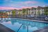 Charming apartment complex with scenic mountain views, featuring a pristine pool surrounded by vibrant orange lounge chairs.