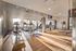 Modern fitness center with abundant natural light, featuring state-of-the-art cardio and strength equipment on sleek wooden flooring.