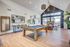 Chic recreational room with a modern pool table, stylish bar seating, and cozy lounge area by a fireplace, featuring expansive windows and elegant decor.