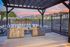 Charming outdoor grilling station with stainless steel barbecues under a pergola, overlooking a serene pool and mountain views.