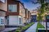 Contemporary townhouses with elegant wood siding and large windows, lined with lush greenery and a sunset backdrop.