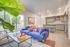Bright and modern open-concept living room and kitchen with large windows, cozy blue sofa, and stylish decor.
