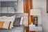 Cozy bedroom corner with stylish wooden headboard, plush pillows, and an elegant bedside table with a modern lamp.