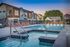 Inviting apartment complex with a sparkling outdoor pool and lounge chairs, framed by beautiful mountain views under a vibrant sky.
