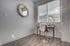Bright and inviting home office with a decorative mirror, cozy desk setup, and sunlight streaming through blinds.