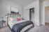 Inviting bedroom with modern decor, featuring a cozy bed adorned with stylish bedding, elegant bedside lamps, and a spacious closet.