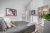 Bright and modern bedroom featuring stylish decor, cozy gray bedding, and an ensuite bathroom with natural lighting.