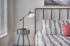 Modern bedroom corner with elegant table lamp on sleek nightstand, featuring stylish black and white bedding and a vibrant accent pillow.