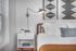 Chic bedroom corner featuring a cozy bed with plush pillows, modern side table, stylish wall lamp, and artistic wall decor for a serene ambiance.
