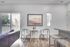 Bright modern living space featuring a cozy dining nook with stylish chairs and artwork, complemented by elegant flooring and abundant natural light.