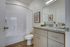 Modern bathroom featuring elegant granite countertops, sleek cabinetry, and a pristine bathtub with stylish artwork on the walls.