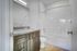 Elegant bathroom featuring a granite countertop, modern fixtures, and a sleek white bathtub with a curved shower rod. Stylish wood cabinetry complements the bright interior.