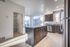 Modern kitchen with sleek dark wood cabinets, granite countertops, and bright natural light from large windows.