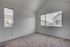 Bright and airy room with plush carpet and large windows offering charming neighborhood views.