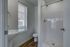Contemporary bathroom featuring a sleek walk-in shower, modern pedestal sink, and natural light through a large window.
