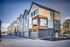Modern townhouse complex with sleek design, large windows, and stylish exterior cladding under a blue sky.