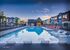 Luxurious community pool surrounded by modern apartments with stylish lounge chairs, set against a tranquil sunset backdrop.