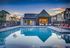 Luxurious community pool with stylish loungers and modern clubhouse at sunset.