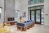 Elegant and inviting living area with a modern fireplace, plush blue sofa, and large windows offering abundant natural light.