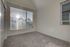 Bright, sunlit room with a large window, plush carpet flooring, and modern charm.