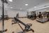 Modern fitness center with state-of-the-art equipment, including treadmills and a weight station, on stylish wood flooring.