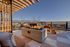 Luxurious rooftop terrace with modern fire pit, panoramic mountain views, and stylish outdoor seating under a pergola.