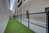 Modern urban outdoor space featuring a secure fenced area with artificial grass for versatile use.
