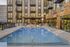 Luxurious apartment complex featuring a sparkling outdoor pool, modern architecture, and stylish seating area.