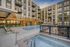 Modern apartment complex with a luxurious outdoor pool and hot tub, surrounded by elegant seating and stylish balconies.
