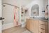 Modern bathroom featuring a sleek wooden vanity, large mirror, and bright shower area with stylish curtain.