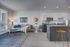 Modern open-plan living area with elegant decor, featuring a cozy gray sofa, vibrant blue accents, sophisticated artwork, and a spacious kitchen with sleek cabinetry.