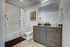 Modern bathroom with sleek wooden vanity, stylish artwork, and plush decor, offering a serene spa-like atmosphere.