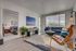 Modern living room with a cozy atmosphere, featuring a stylish seating area, large windows for natural light, and an adjacent bedroom view.