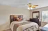 Elegant bedroom with a ceiling fan, featuring a plush bed and stylish wooden furniture, creating a cozy and inviting atmosphere.