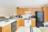 Bright and inviting kitchen with classic wooden cabinets, modern appliances, and a spacious countertop, perfect for culinary enthusiasts.