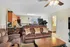 Inviting living room with plush sofas, stylish decor, and contemporary ceiling fan, adjacent to a cozy kitchen space.