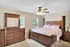 Cozy bedroom featuring elegant wooden furniture, a plush bed with soft bedding, and soothing natural light from twin windows.