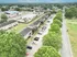 Aerial view of a charming apartment complex with neatly arranged buildings, lush greenery, and ample parking space, offering a serene and welcoming neighborhood atmosphere.