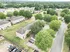Charming aerial view of a lush green neighborhood with modern townhouses, ample parking, and vibrant trees lining the streets.