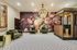 Luxurious apartment lobby featuring elegant green velvet seating, a grand floral mural, and a vintage-style chandelier.