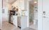 Modern kitchenette with sleek white cabinets, stainless steel appliances, and a stylish subway-tiled bathroom.