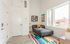 Bright and modern living room with large windows, featuring a gray sofa and colorful striped rug, perfect for vibrant city living.