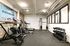 Modern fitness room equipped with state-of-the-art gym equipment, including treadmills, weight benches, and dumbbells, set against a stylish exposed brick wall.