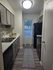 Modern kitchen with sleek cabinetry, stainless steel appliances, and elegant lighting. Features a stylish backsplash and a cozy rug accentuating the wooden floor.