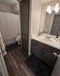 Elegant bathroom with modern fixtures, spacious counter, and chic storage cabinets highlighted by warm lighting.