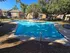 Inviting outdoor pool area with clear blue water, surrounded by lush greenery and modern apartment buildings.