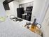 Chic modern kitchen with elegant granite countertops, sleek black appliances, and a welcoming drink setup, perfect for entertaining.