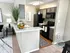 Charming kitchen with modern appliances, sleek gray cabinets, and a cozy breakfast bar, accentuated by vibrant greenery and stylish decor.